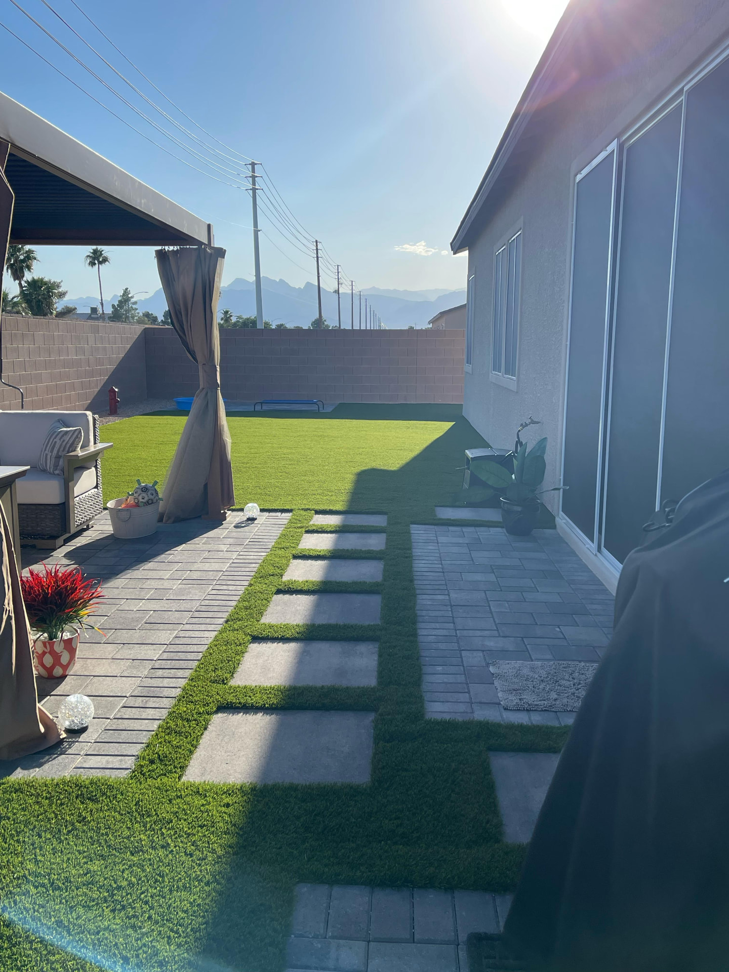Turf side yard with paver stepping stones and a shaded seating area