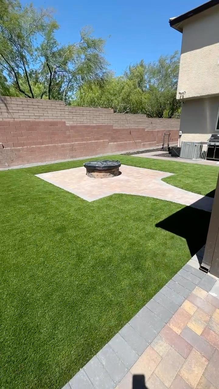 Artificial turf backyard with a paver fire pit island